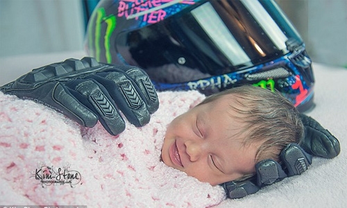 Baby girl smiling after being wrapped in her late father's motorcycle gloves